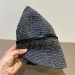 Detail view of a stylish dark grey knit bucket hat with a black leather strap, cozy and chic.
