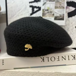 Schwarze Strick-Baretthut für Damen, elegantes Lochmuster mit schicker goldener Blattbrosche.