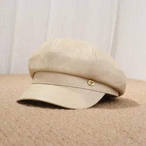 Detalle de primer plano de gorra de vendedor de periódicos de cuero PU beige con chapa metal.