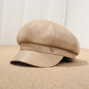 Vista detallada de la gorra baker boy de cuero PU beige con el botón metálico elegante.