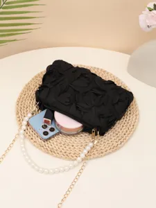 Exquisite detail of black evening handbag featuring fabric roses and elegant pearl chain strap.