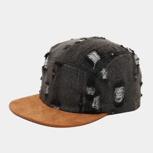 Primer plano de la gorra 5 paneles de denim desgastado con visera de antelina marrón.