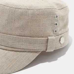 Vista detallada de gorra plana de lino con ojales metálicos y botón decorativo.