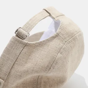 Detalle de la hebilla metálica ajustable y la textura de lino de la gorra plana retro.