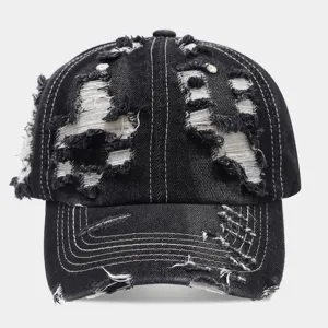 Primer plano detalle de la gorra de béisbol de denim negro lavado con roturas y uso.