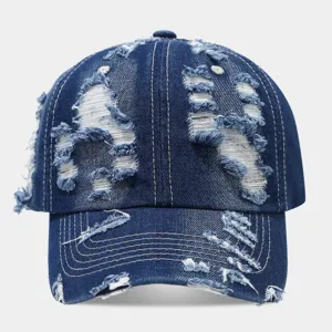 Vista detallada de la gorra de béisbol de mezclilla desgastada con roturas y lavado.