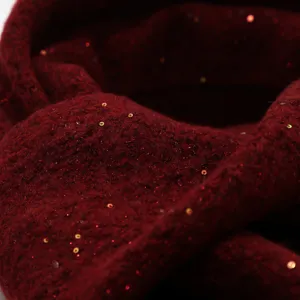 Primer plano detallado de tejido de punto rojo oscuro con lentejuelas brillantes.