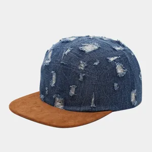 Vista detallada de gorra 5 paneles de denim desgastado con visera plana de ante marrón estilo.