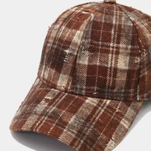 Close-up detail shot of brown distressed plaid baseball cap with raw edge and texture.