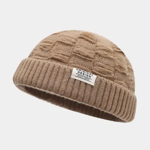 Gedetailleerd overzicht van een stijlvolle khaki gebreide muts met textuur en label.