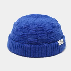 Close-up detail van blauwe gebreide docker muts rand met origineel ontworpen textiellabel.