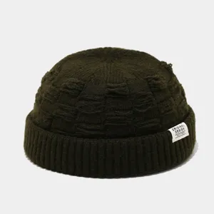 Donkergroene gebreide docker muts met gestructureerd patroon en geweven label detail voor herfst.