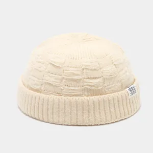 Gedetailleerd uitzicht van een beige gebreide miki muts met label, warm en trendy streetwear.