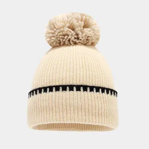 Primer plano del gorro de invierno de punto con pompón y franja negra de contraste.
