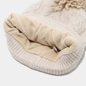 Primer plano del detalle interior de gorro de punto forrado con pompón térmico cálido.