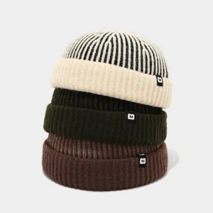 Gestrickte Docker Cap Detailansicht von gestapelten gestreiften Mützen mit M Label.