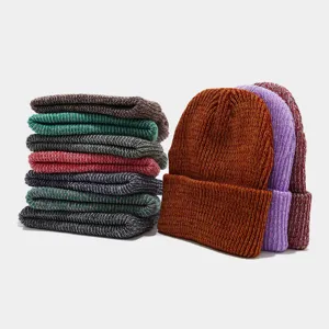 Vista detallada de gorros de punto melange de colores, apilados y presentados para el frío.