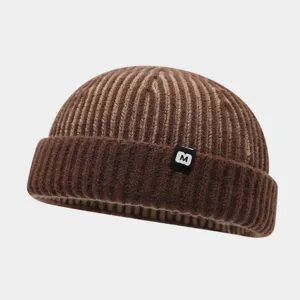 Detailansicht der braunen gestreiften Strickmütze mit kleinem M-Etikett, Unisex Wintermütze.
