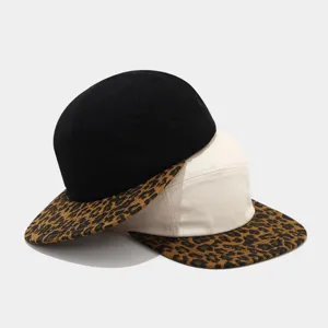 Detail shot of five-panel flat brim hats featuring stylish leopard print brims and solid crowns.