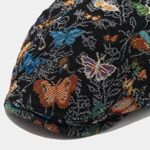 Close-up of a retro women's black flat cap featuring colorful butterfly jacquard weaving details.