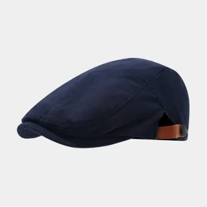 Gedetailleerde close-up van de donkerblauwe platte pet met gestructureerde stof en lederen gesp.