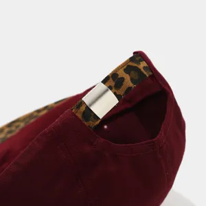 Close-up view of the adjustable leopard print strap and metal buckle on a burgundy hat.