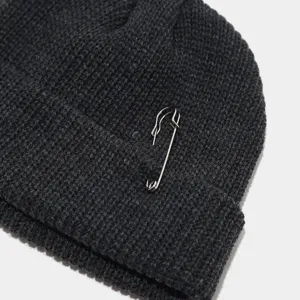 Grijze gebreide muts detail close-up, gezellige wintermuts met metalen veiligheidsspeld accessoire.