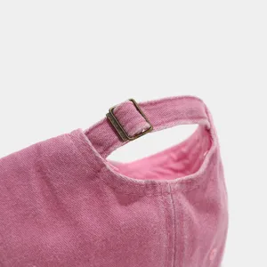 Close-up detail of pink washed baseball dad hat adjustable metal buckle, vintage texture.