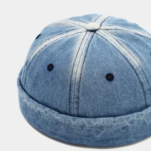 Close-up detail of the washed denim miki hat showing panel stitching, top button, and fabric texture clearly.