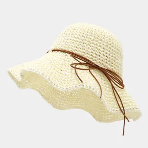Gros plan d'un chapeau de paille beige tissé avec un ruban nœud en cuir marron élégant.