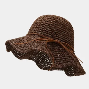 Gros plan détaillé du chapeau de paille tressé marron avec un élégant nœud en cuir.