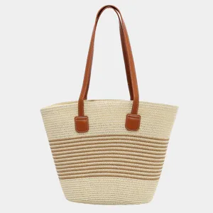 Detalle de bolso de paja con textura tejida, asas de cuero marrón y rayas multicolor.