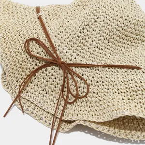 Chapeau cloche en paille respirant avec nœud, vue rapprochée de la texture pour plage.