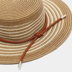 Primer plano de sombrero de paja para mujer bicolor con cordón decorativo de cuero marrón.