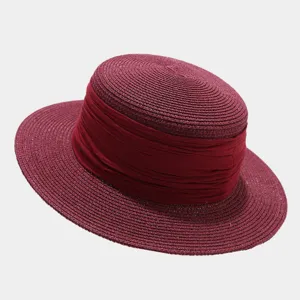 Detailed shot of a wine red flat top straw hat featuring a wide fabric ribbon decoration.