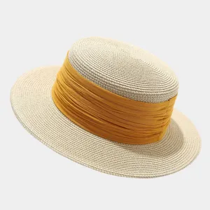 Close-up of French vintage flat top straw hat with yellow ribbon for beach summer sun protection.