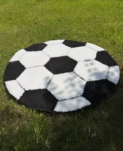 Close-up detail of soft black and white soccer rug on lawn, cozy home decor floor mat texture.