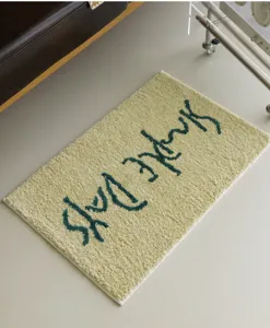 Grüne flauschige Badematte Detail, weicher Plüschteppich mit minimalistischem Textdesign.