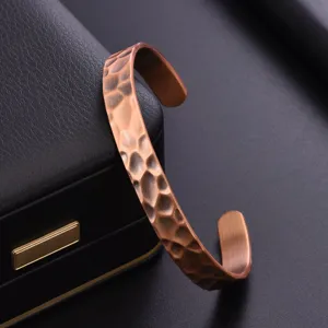 Close-up of hammered copper cuff bracelet, unique open bangle design with textured finish.
