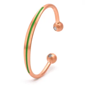 Close-up detail of open copper magnetic bracelet with green enamel stripe and magnets.
