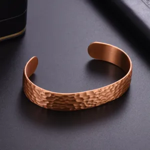 Detailed shot of copper hammered open cuff bracelet, showcasing unique textured surface design.