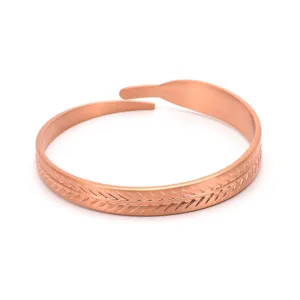 Detail view of the elegant open copper cuff bracelet featuring a minimalist feather pattern.
