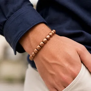 Close-up detail shot of a stylish pure copper bead bracelet worn on wrist, smooth metallic finish.