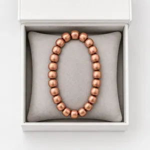 Detailed view of a pure copper bead bracelet displayed on a soft grey cushion inside a white box.
