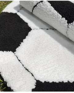 Detailed close-up of a thick black and white soccer pattern plush carpet, soft and absorbent.