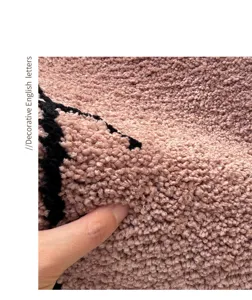 Detailed view of a soft fluffy tufted bathroom floor mat in pink with black pattern.