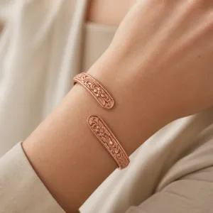 Close-up detail of the vintage carved open copper bracelet on wrist showing texture.