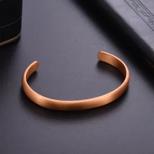 Macro detail of minimalist copper open cuff bracelet showing brushed matte metal finish.