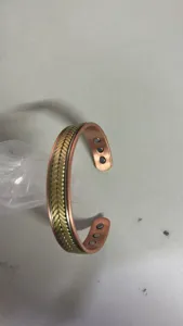 Close up detail of copper magnetic therapy bracelet with wheat weave pattern and embedded magnets.