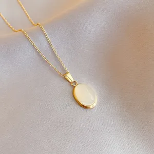 Detailed close-up of gold stainless steel necklace with oval white cat eye stone pendant.